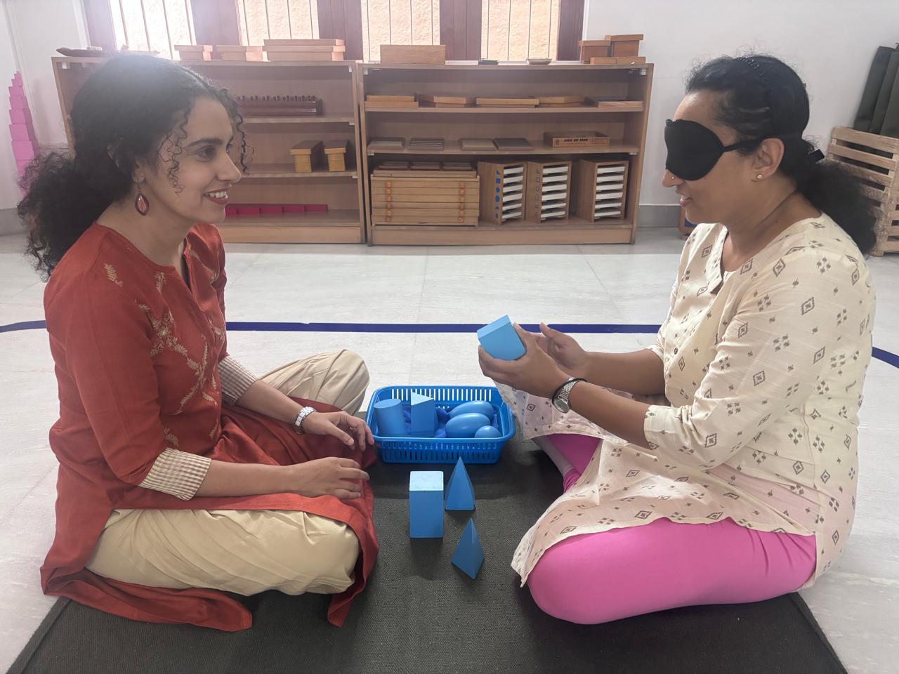 Montessori trainer and trainee exchanging a blue sensorial material during practice