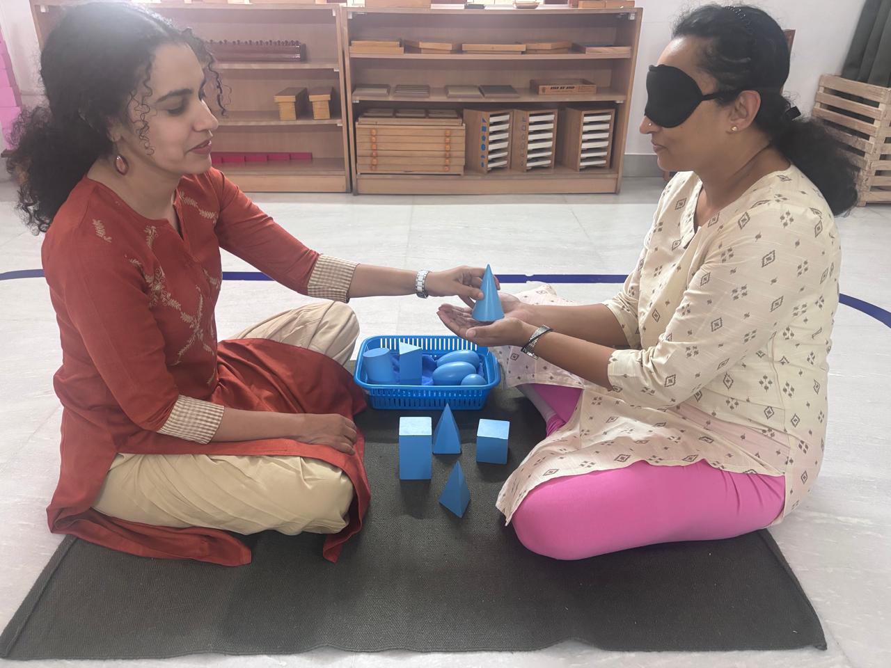 Two FTTA trainees practising a blue Montessori sensorial material presentation