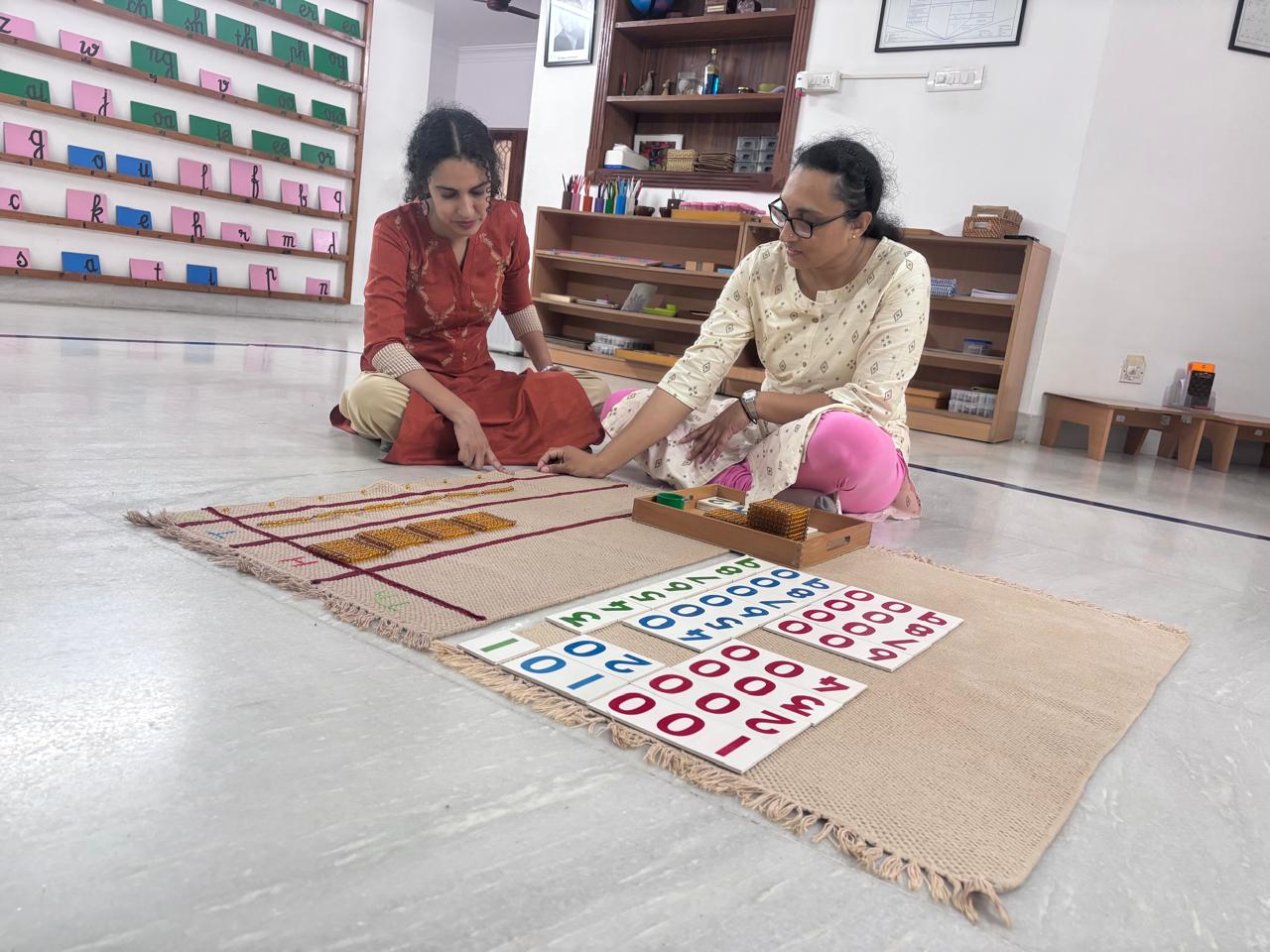 Two trainees practising Montessori math materials in the FTTA classroom