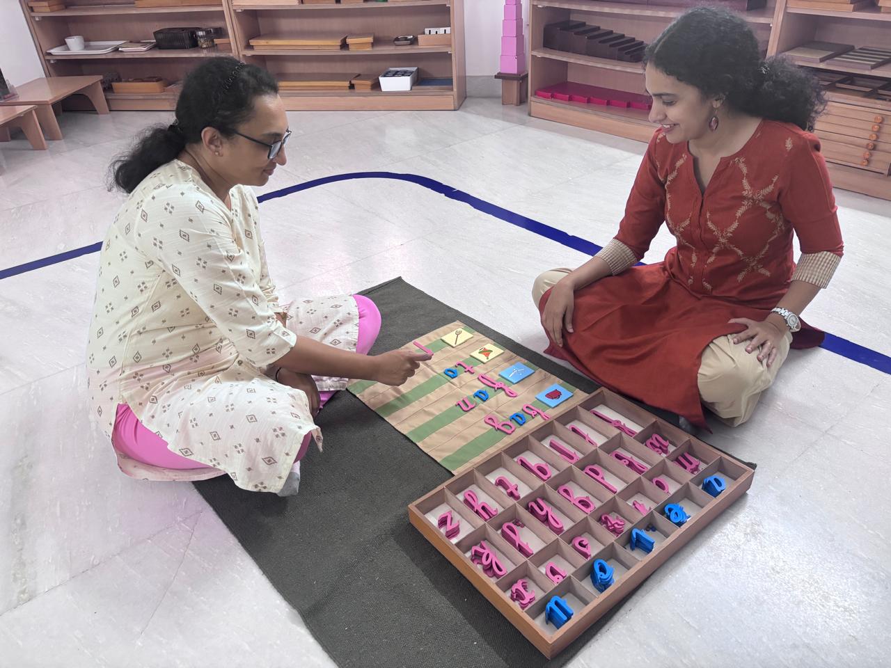 Montessori trainee receiving a bead material demonstration from an FTTA trainer